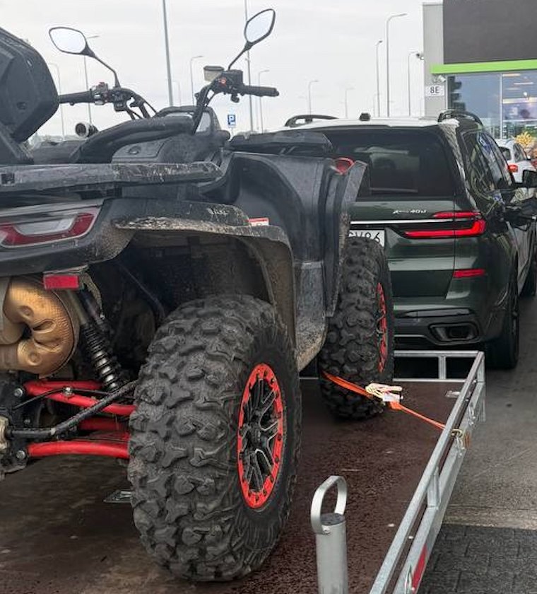 Zabłocony quad na przyczepie w drodze w teren